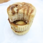 Stack of mini caramel swirl cheesecakes with a bite taken out of the top to reveal the smooth and cream center.