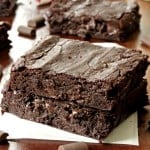 Chocolate chunk brownies sliced and stacked on parchment paper.