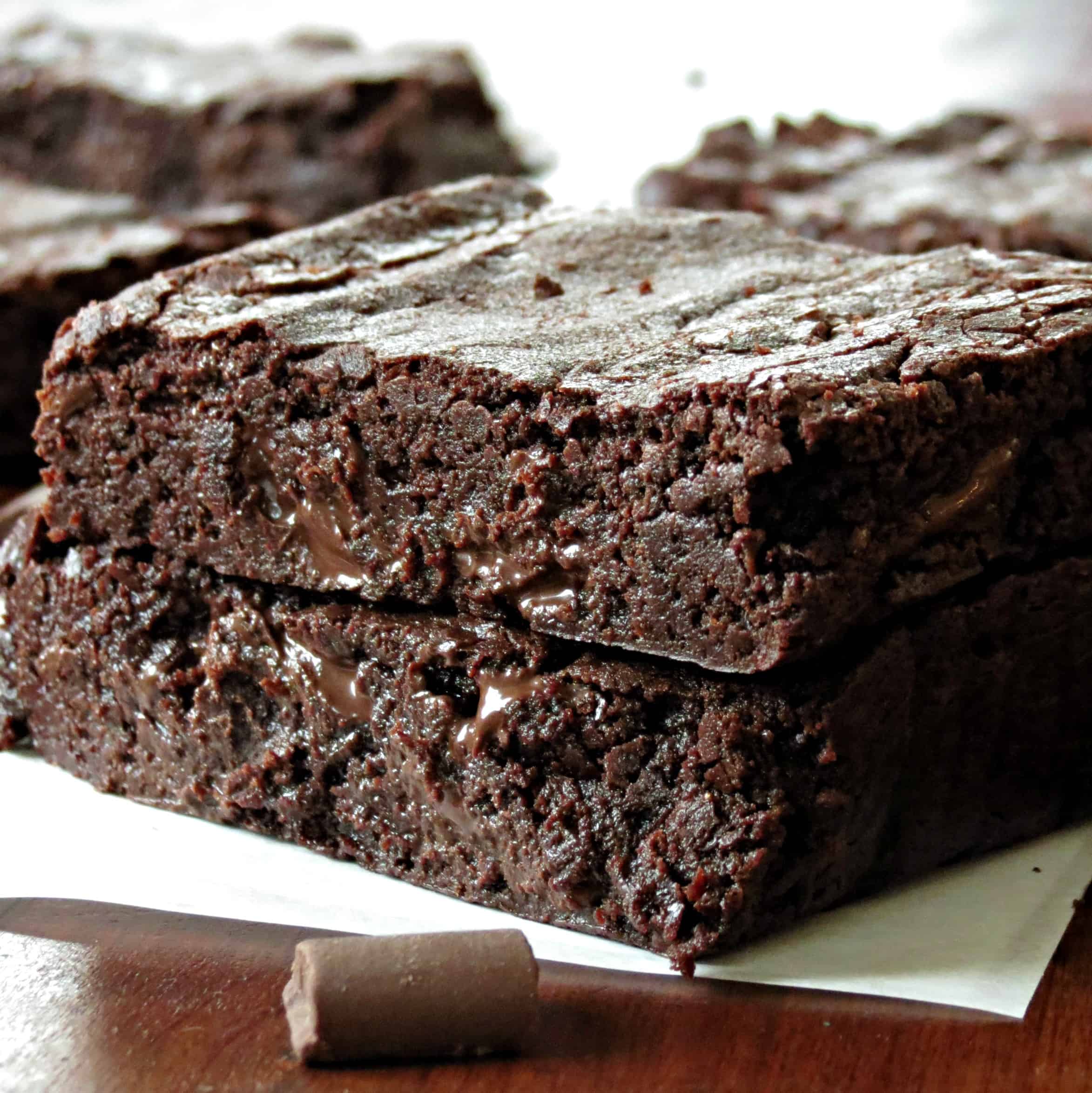 Chocolate chunk brownies sliced and stacked on parchment paper.