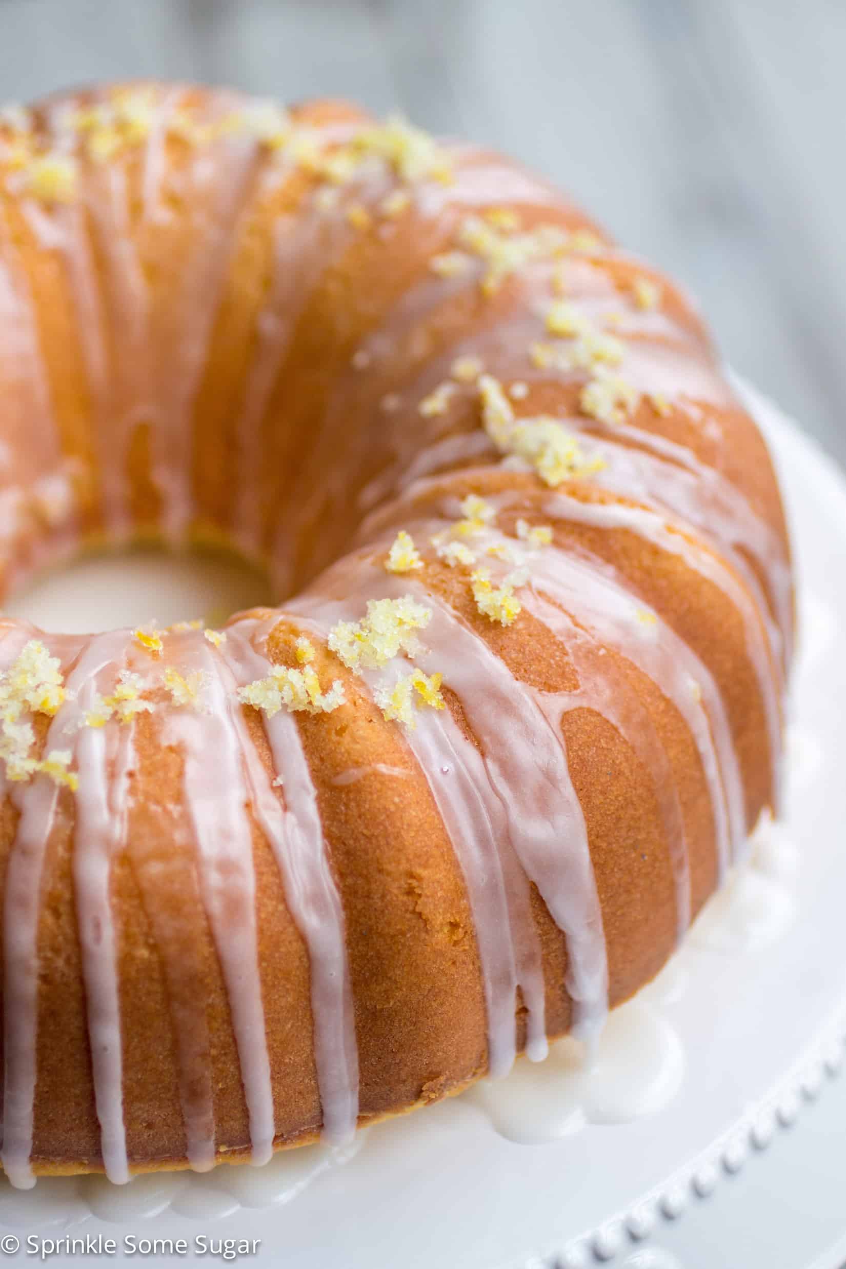 Lemon bundt cake on a white cake stand.