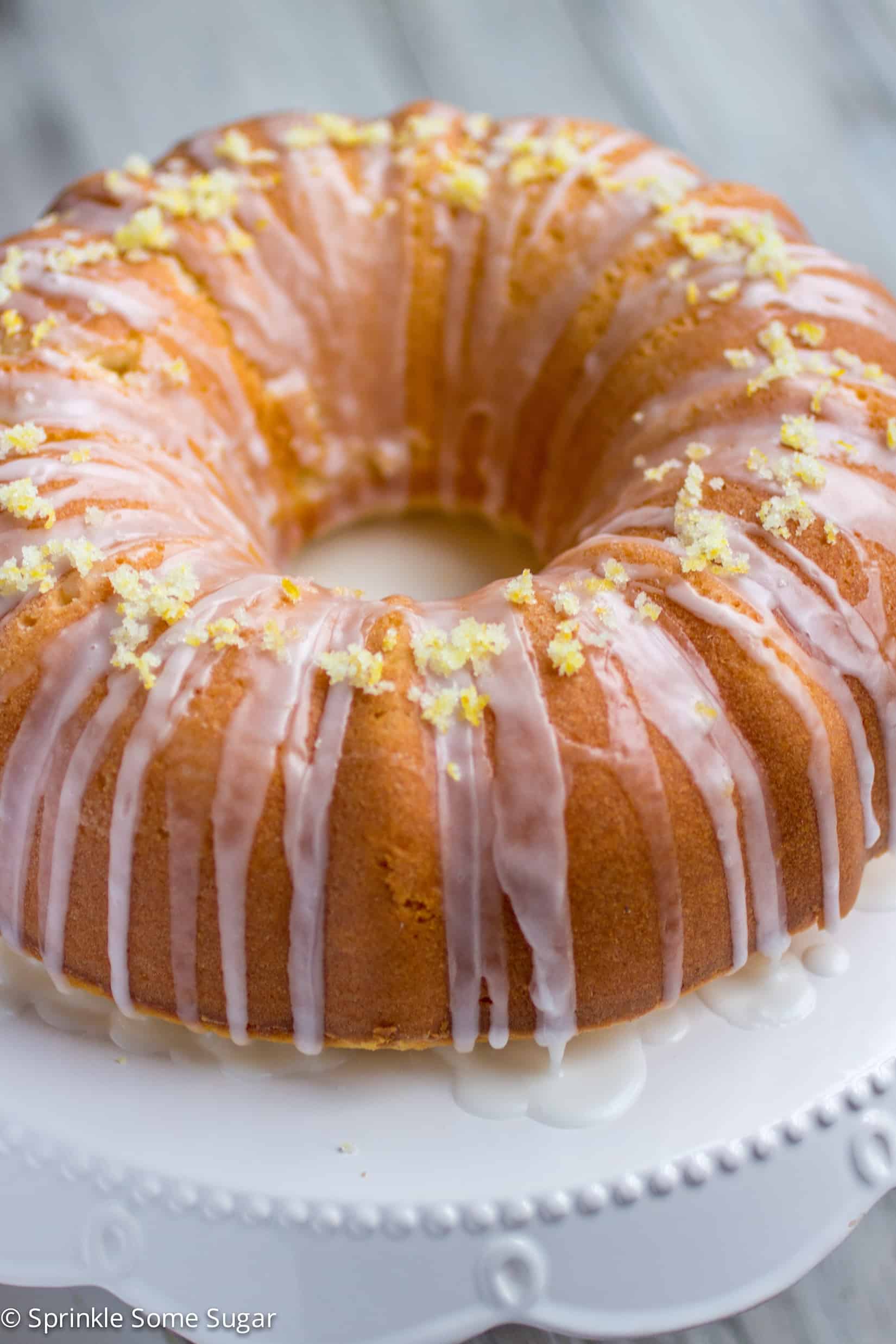 Lemon bundt cake whole cake before slicing on a white cake stand.