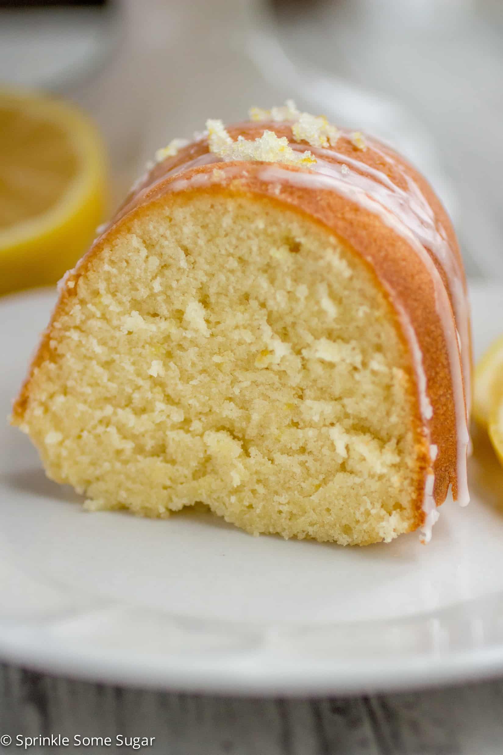 Slice of glazed lemon bundt cake on a white plate.