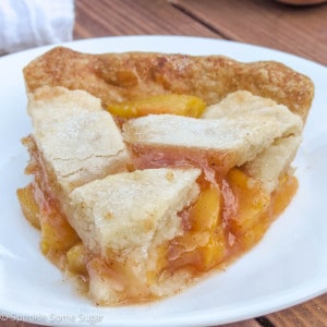 Slice of peach pie on a white plate.