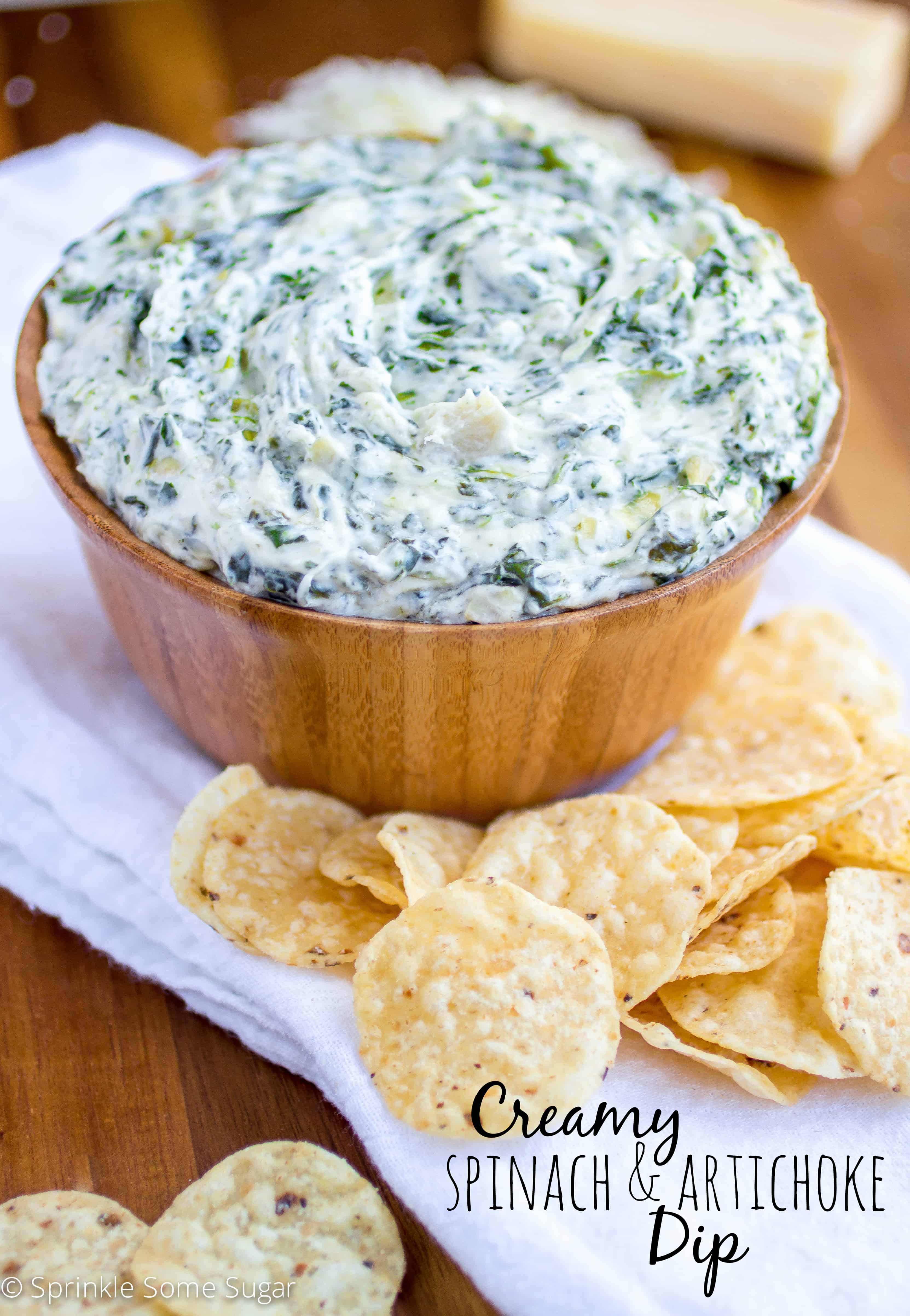 Spinach and artichoke dip in a wood bowl with chips surrounding it.