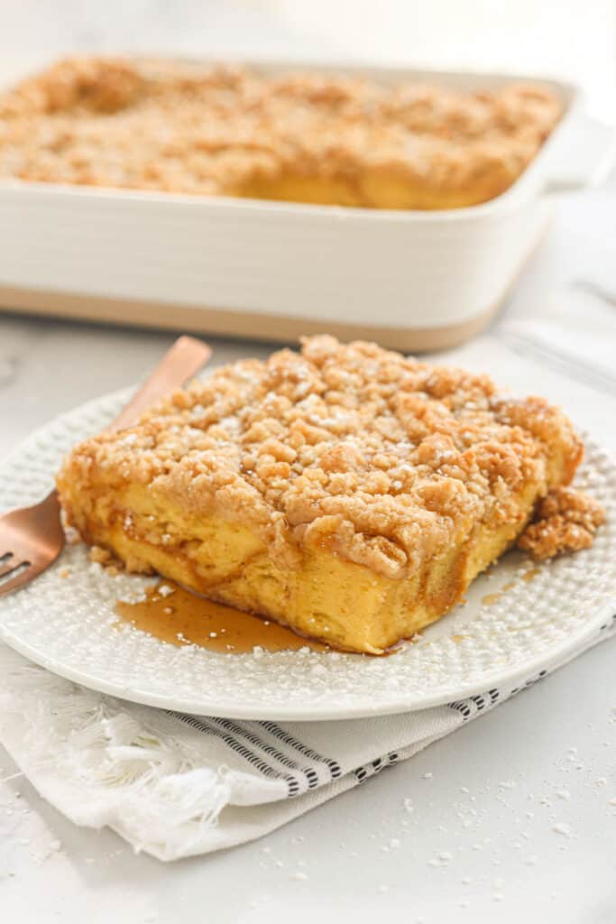 Slice of overnight French toast on a plate with maple syrup.