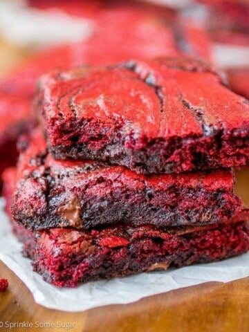 Red velvet brownies stacked on top of one another with a bite taken out of the top one.