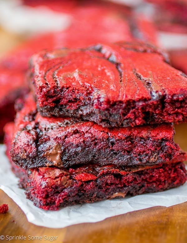 Red velvet brownies stacked on top of one another with a bite taken out of the top one.
