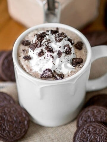 Mug of oreo hot chocolate with oreos around it.