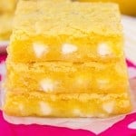 Lemon Gooey bars stacked on a pink napkin.