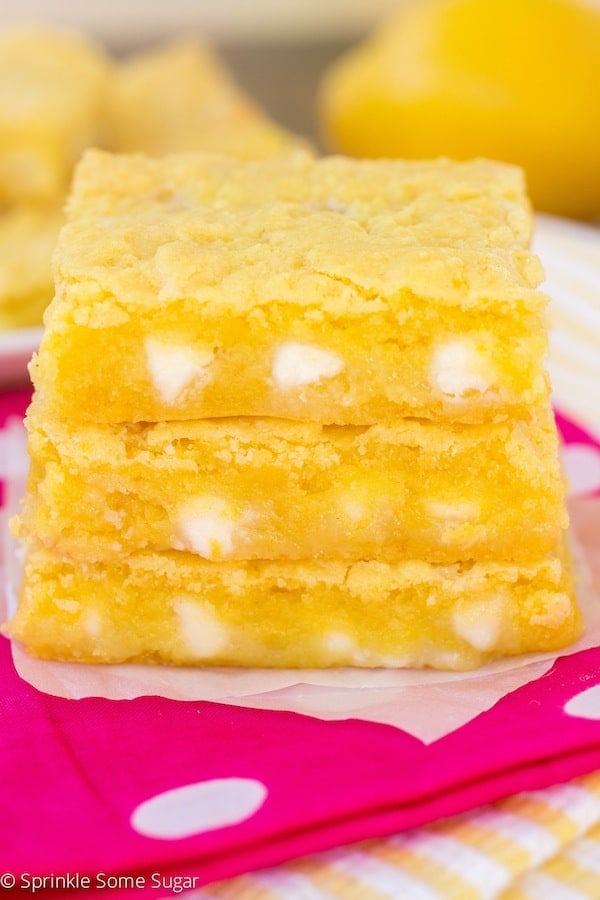 Lemon Gooey bars stacked on a pink napkin.