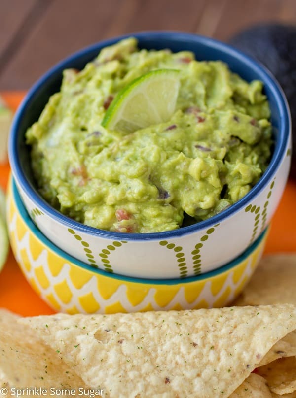 guacamole in a bowl with a lime on top.