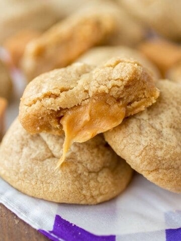 Caramel stuffed peanut butter cookie with a bite taken out to reveal gooey caramel inside.