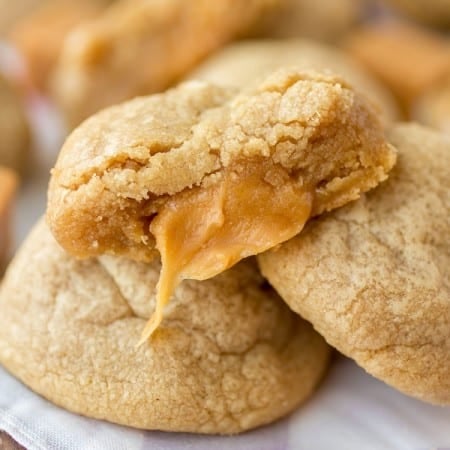 Caramel stuffed peanut butter cookie with a bite taken out to reveal gooey caramel inside.