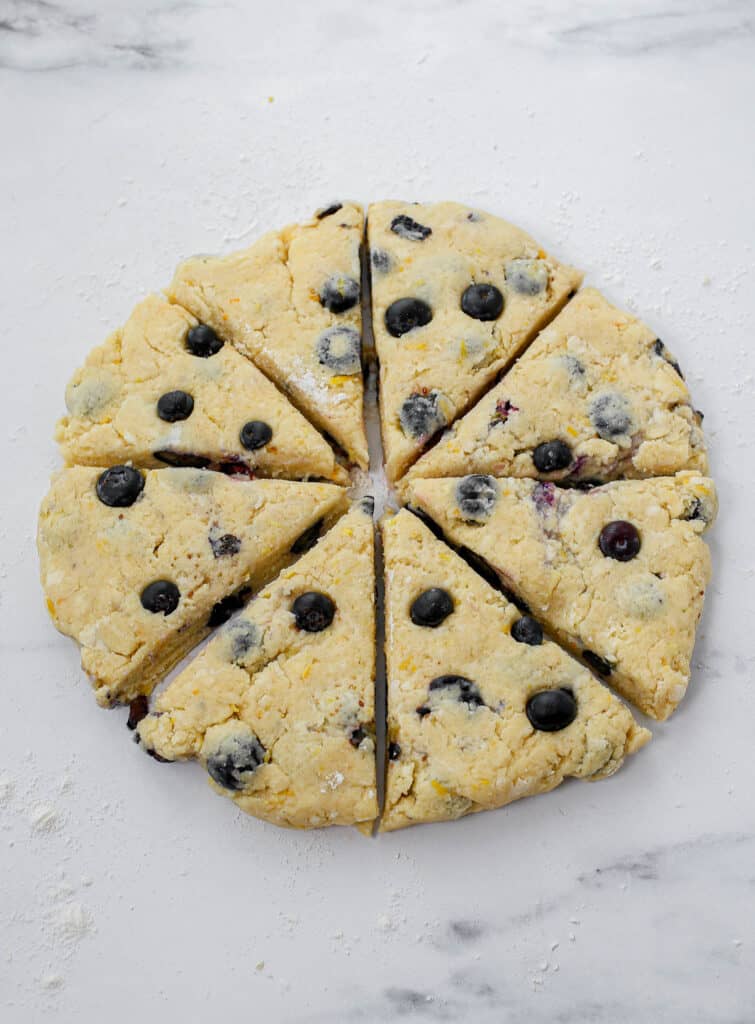 Lemon blueberry scones flattened out into a circle and cut into 8 pieces like a pizza.