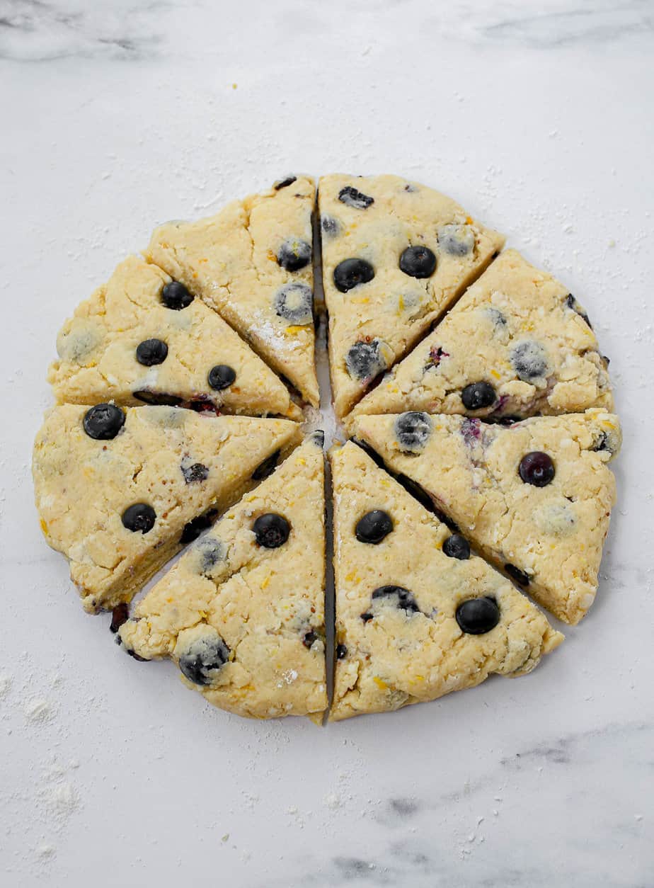 Lemon blueberry scones flattened out into a circle and cut into 8 pieces like a pizza.