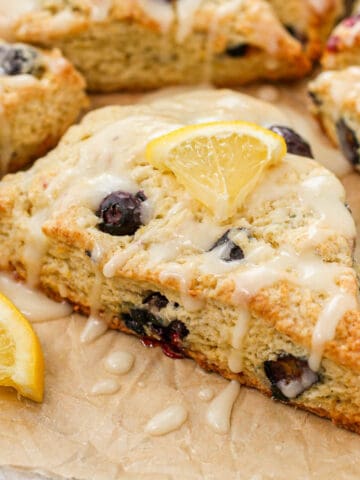 Lemon blueberry scones on a piece of parchment paper feat.