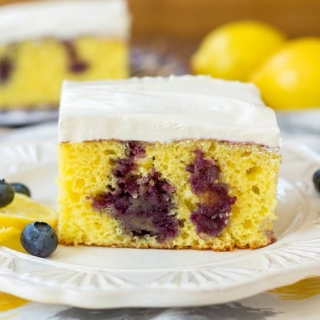 Lemon poke cake with blueberries slice on a plate.