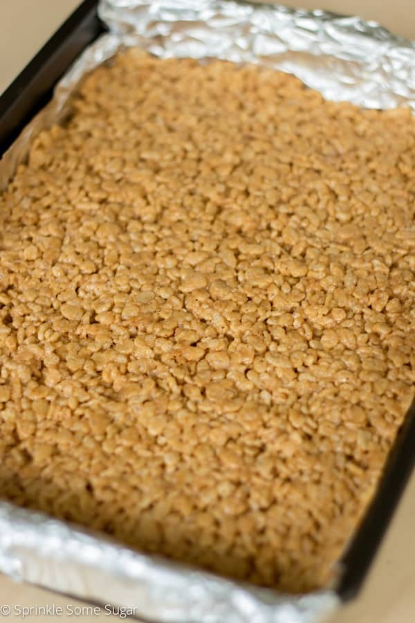 Peanut butter honey Rice Krispie treats pressed into pan ready to be sliced into bars.