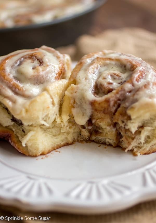 Soft and fluffy cinnamon rolls with cream cheese frosting on a white plate.