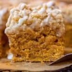 Slice of pumpkin streusel coffee cake on a piece of brown parchment paper on a metal spatula.