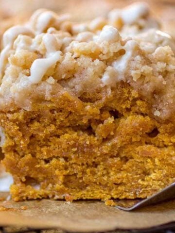 Slice of pumpkin streusel coffee cake on a piece of brown parchment paper on a metal spatula.