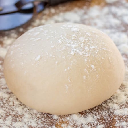 Pizza dough on floured counter.