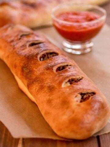 Italian sausage and provolone Stromboli on a piece of parchment paper.
