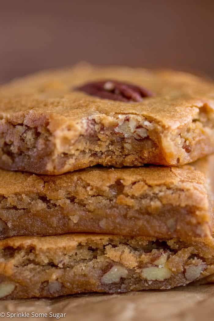 Browned butter pecan blondies stacked with a bite taken out of the top one.