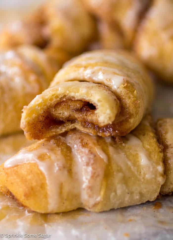 Cinnamon roll crescents stacked on one another with bite taken out of top to see gooey center.
