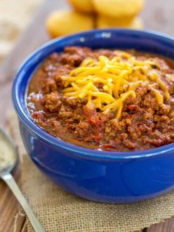 chili in a blue bowl with cheddar cheese on top
