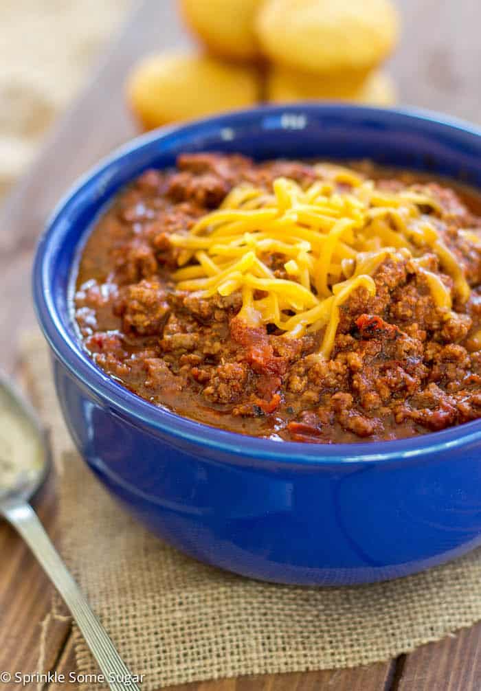 chili in a blue bowl with cheddar cheese on top