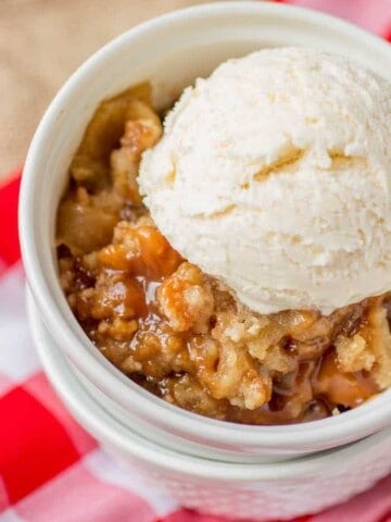 Caramel apple crisp with a scoop of vanilla ice cream in a bowl.