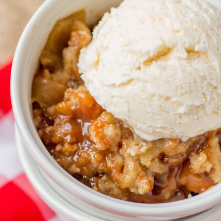 Caramel apple crisp with a scoop of vanilla ice cream in a bowl.