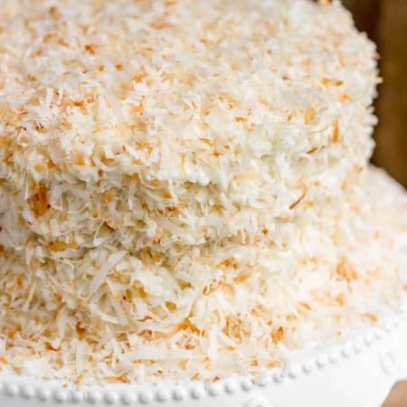 The fluffiest coconut cake filled with homemade lemon curd, topped with tangy coconut cream cheese frosting and covered in toasted coconut.