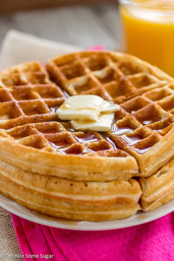 Waffles on a plate with butter and syrup on top.