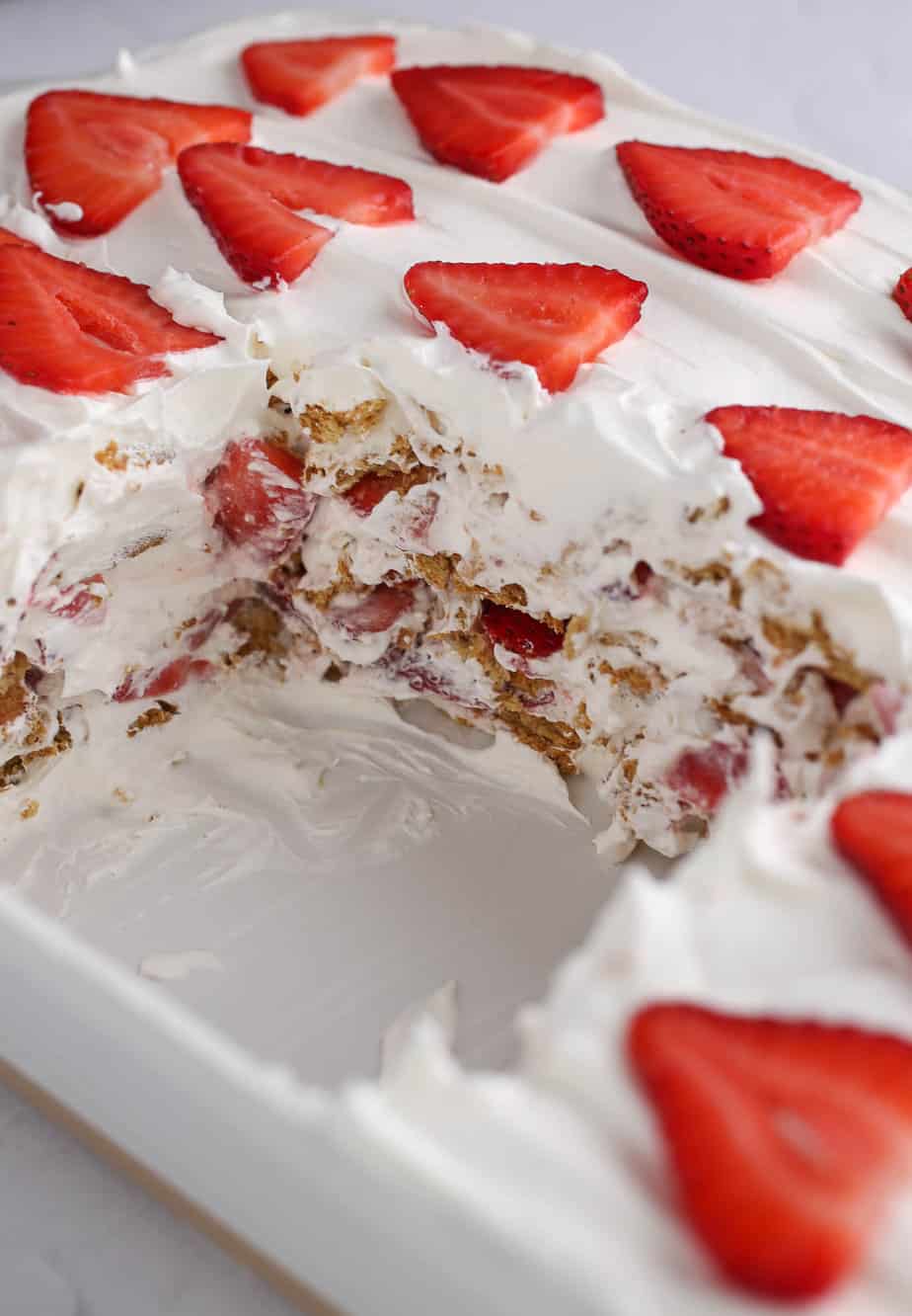 Strawberry icebox cake in the pan with a slice taken out.