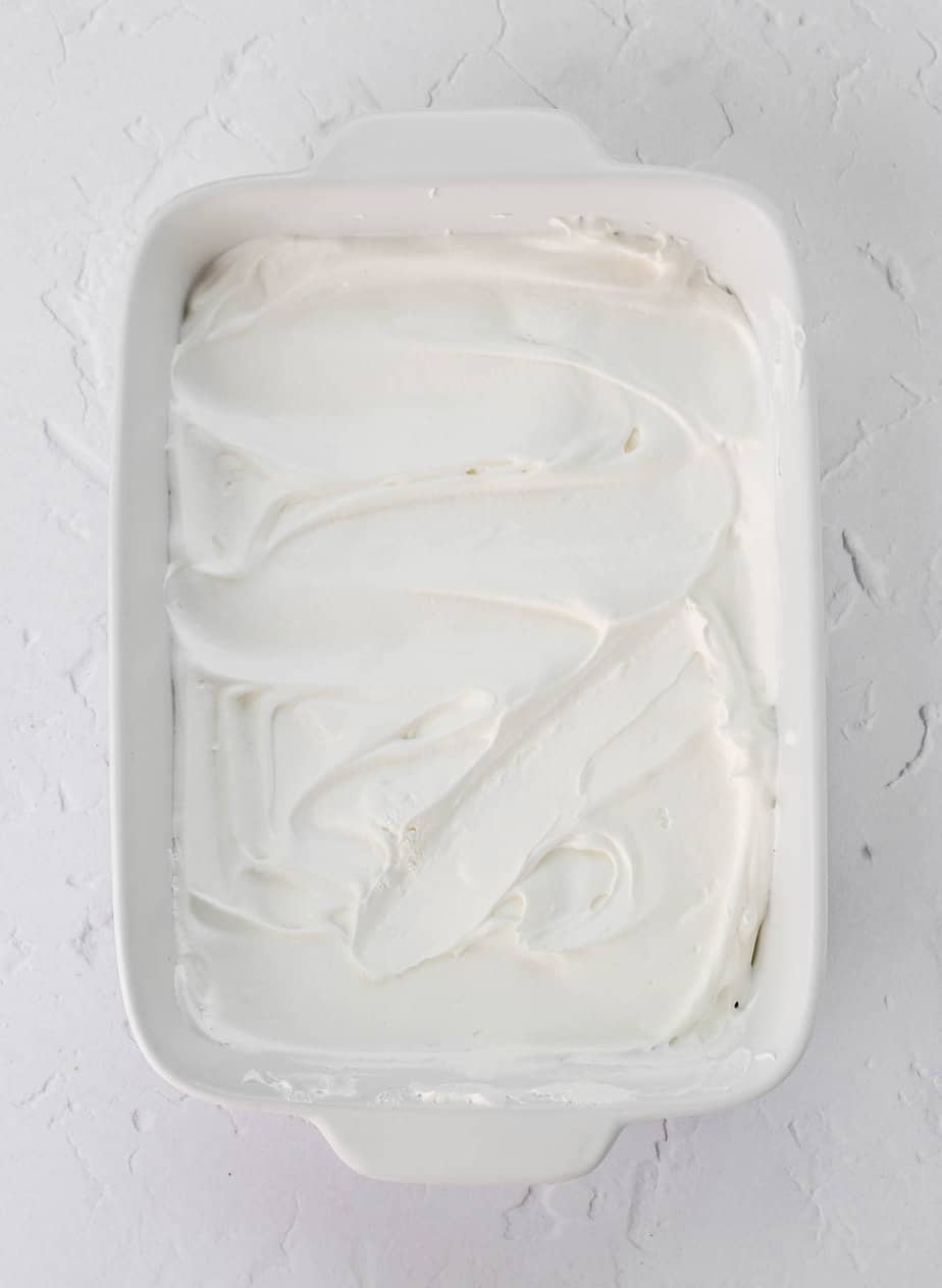 Layer of whipped topping in a baking dish.