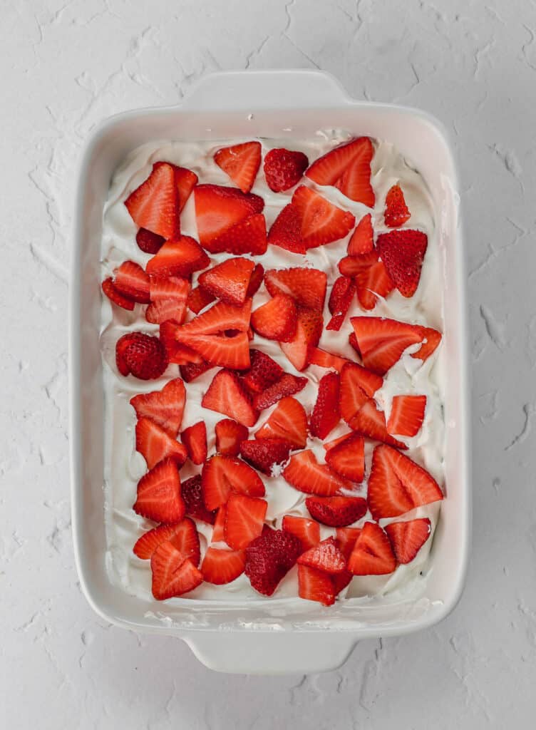 Layers of strawberries and whipped cream in a baking dish.