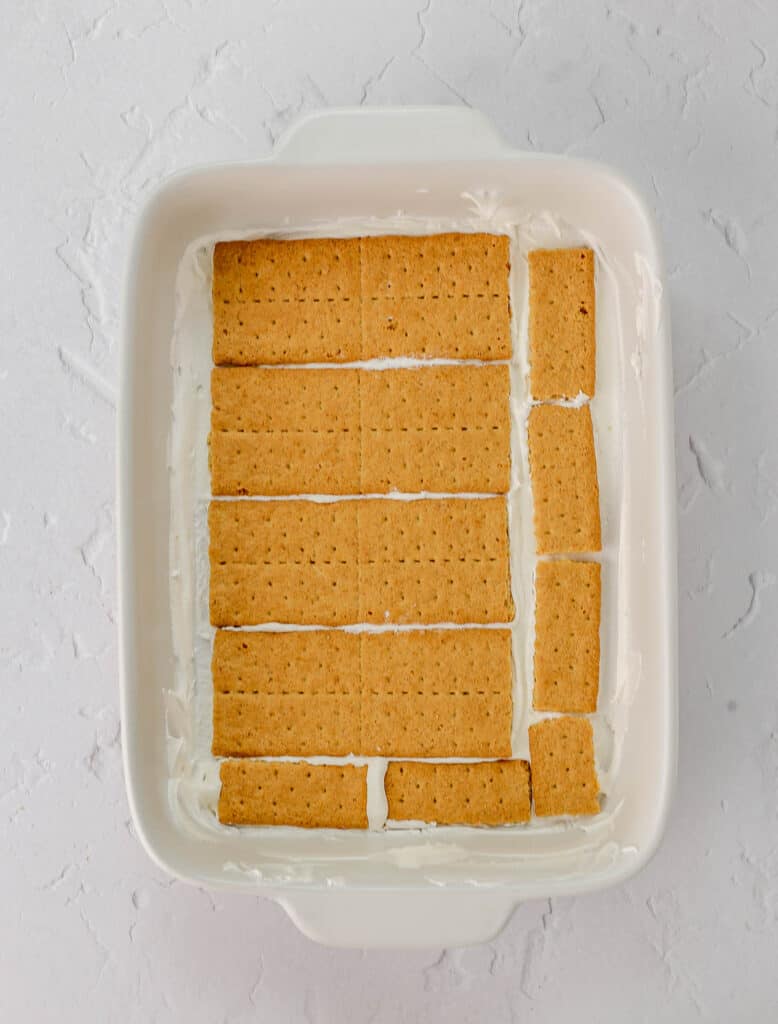 Layers of strawberries, whipped cream and graham crackers in a baking dish.