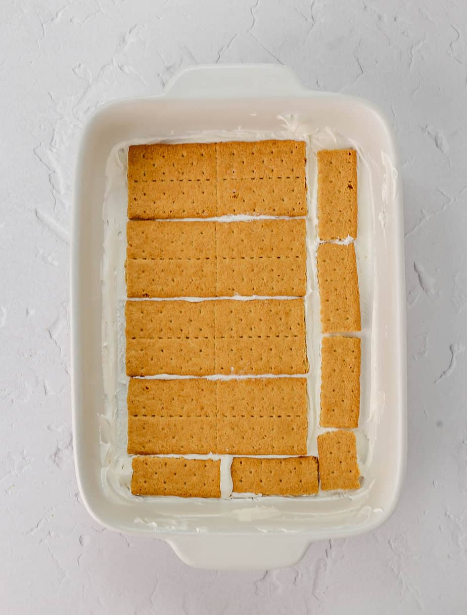 Layers of strawberries, whipped cream and graham crackers in a baking dish.