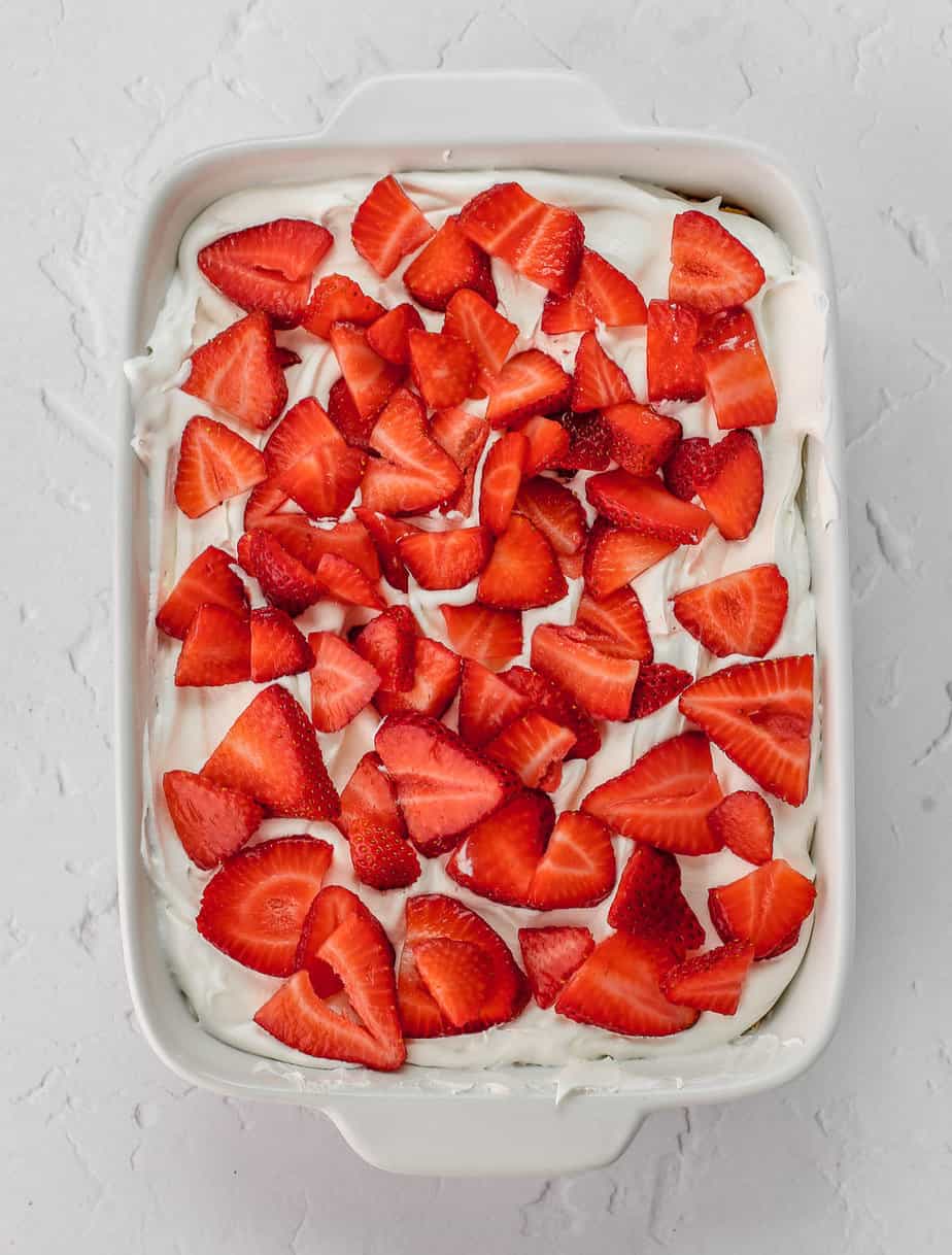 Layers of strawberries, whipped cream and graham crackers in a baking dish.