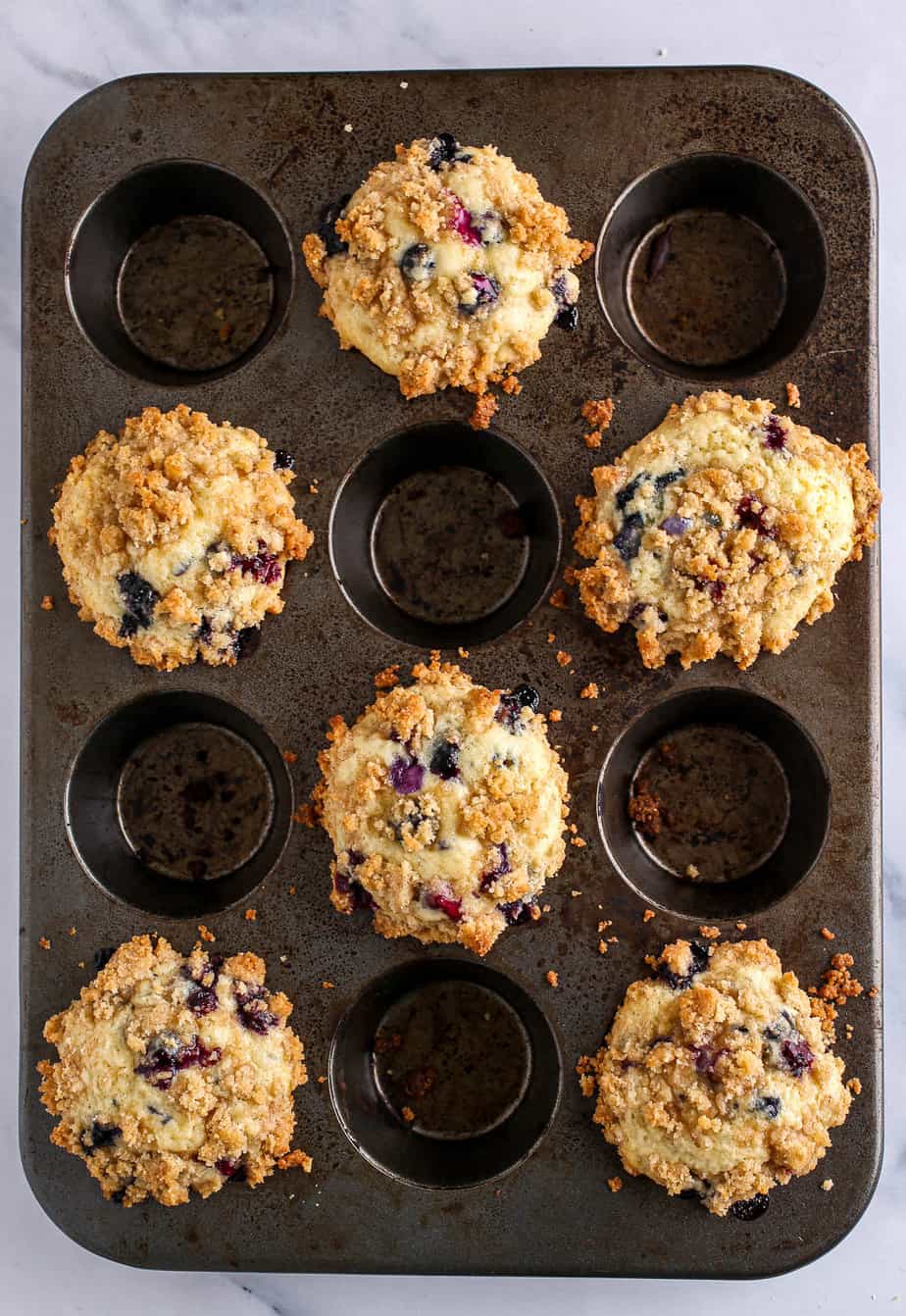 Blueberry Muffins With Crumb Topping overhead shot in muffin pan after being baked.