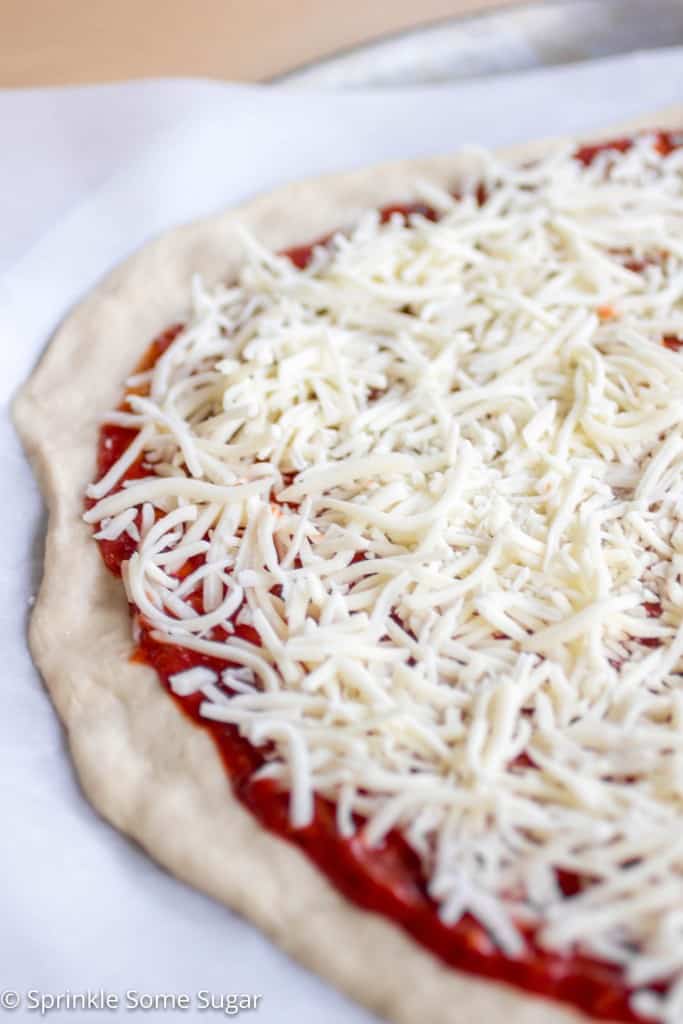 Pizza dough with sauce and cheese before baking.