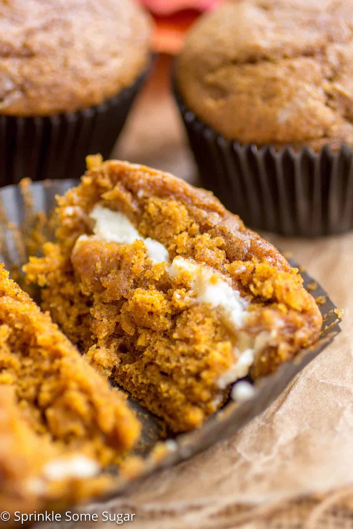 Pumpkin cheesecake swirl muffin cut in half to reveal cream cheese swirl inside.