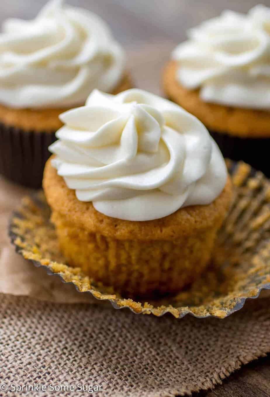 Pumpkin spice cupcakes on a piece or brown parchment paper with the liner unwrapped.