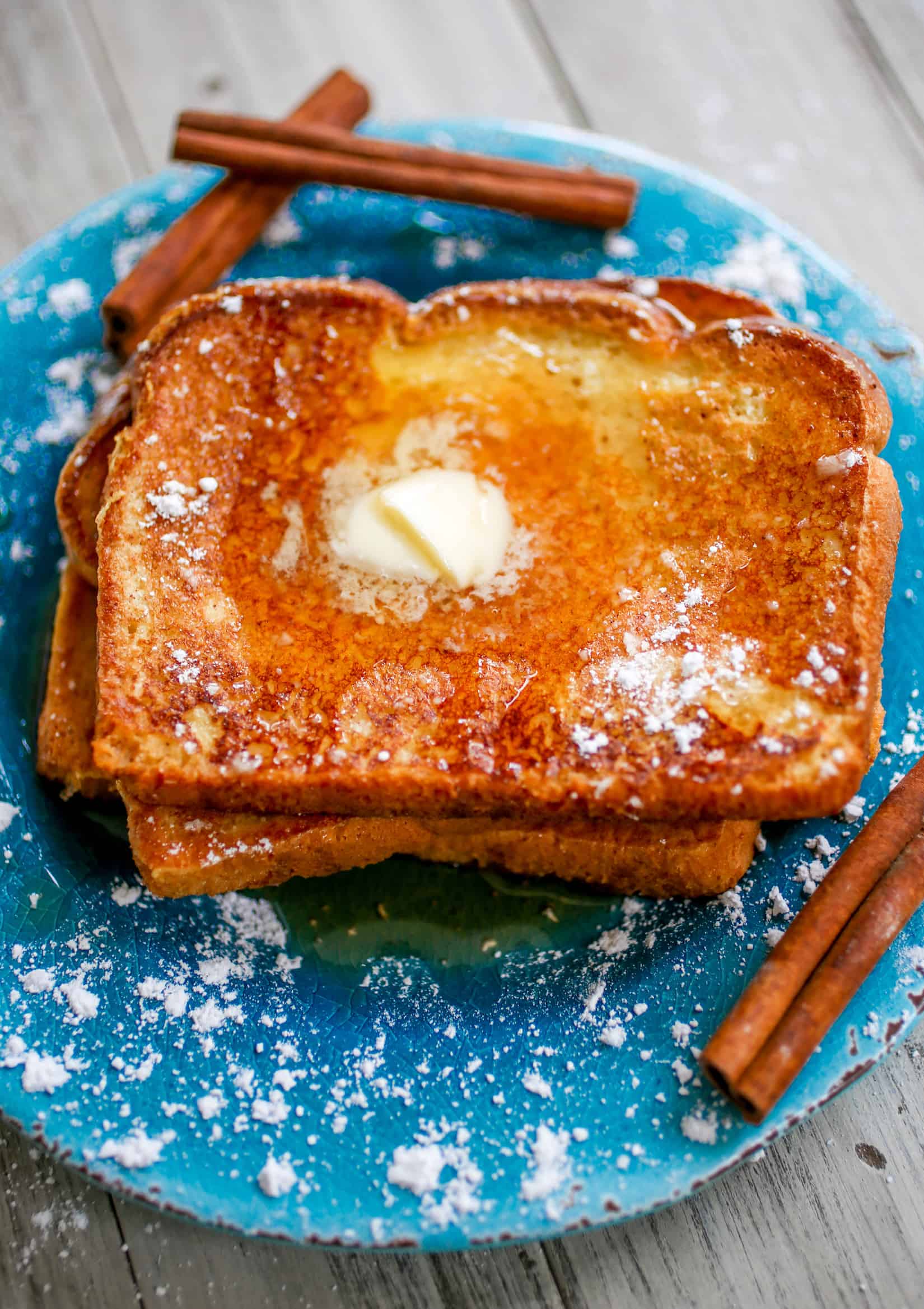 Eggnog French toast stacked on a blue plate.