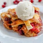 Cranberry Apple Pie with a scoop of vanilla ice cream on top on a plate.