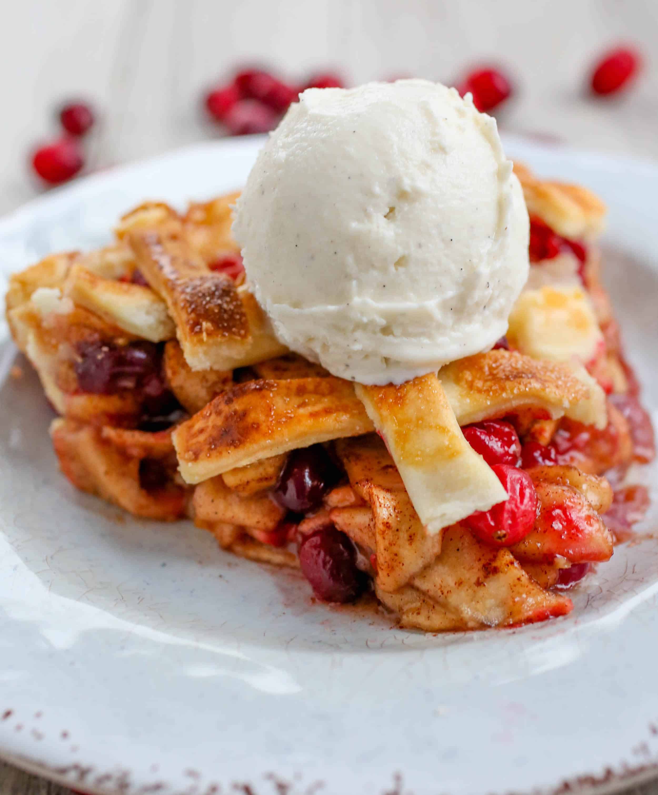 Cranberry Apple Pie with a scoop of vanilla ice cream on top on a plate.