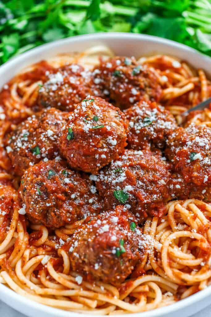 Meatballs on a bed of spaghetti with grated cheese sprinkled on top.