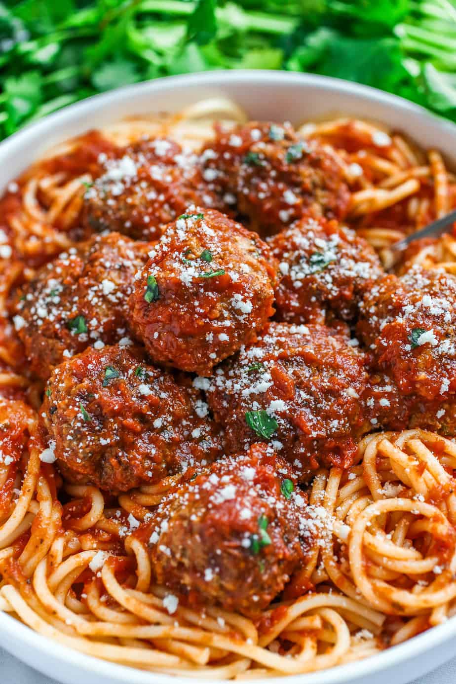 Meatballs on a bed of spaghetti with grated cheese sprinkled on top.